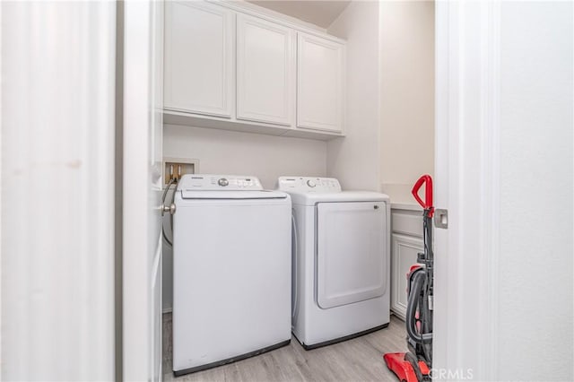 laundry area with cabinets, light hardwood / wood-style floors, and washing machine and dryer