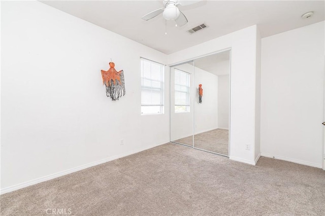 unfurnished bedroom featuring light colored carpet, a closet, and ceiling fan