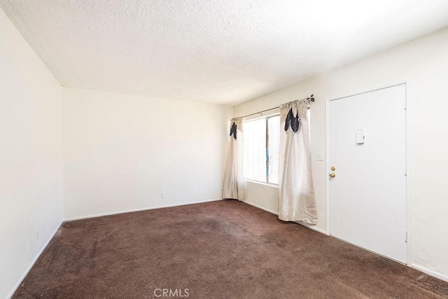 carpeted empty room featuring a textured ceiling