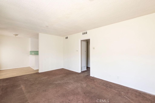 unfurnished room featuring dark carpet and a textured ceiling