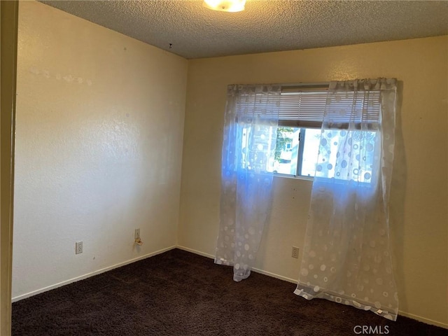 empty room with a textured ceiling and dark colored carpet