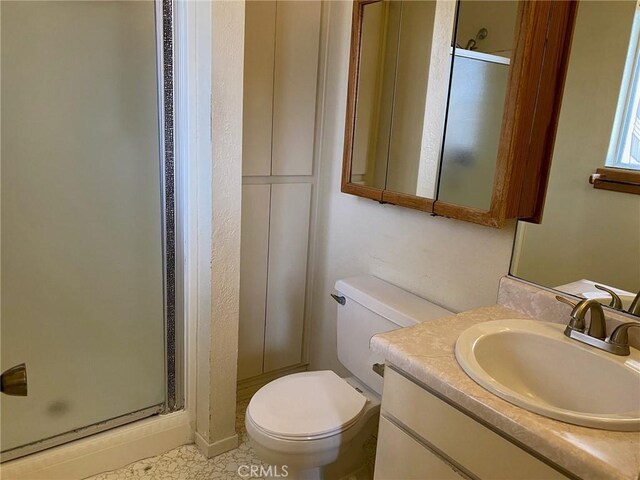 bathroom featuring vanity, a shower with door, and toilet