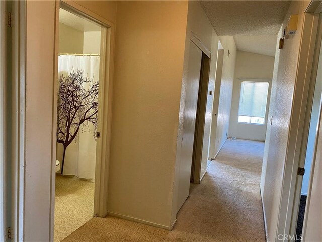 hall with light carpet and a textured ceiling