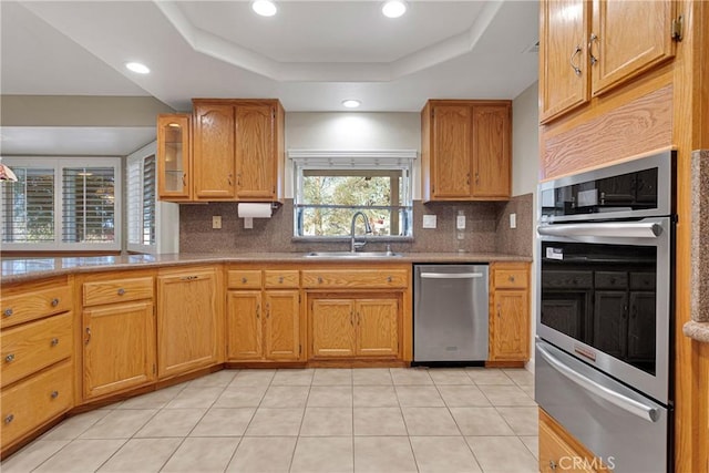 kitchen featuring light tile patterned flooring, sink, tasteful backsplash, a raised ceiling, and stainless steel appliances