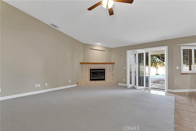 unfurnished living room with a tile fireplace, light tile patterned floors, and ceiling fan