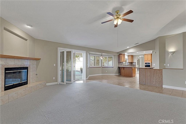 unfurnished living room featuring ceiling fan, a fireplace, vaulted ceiling, and light carpet