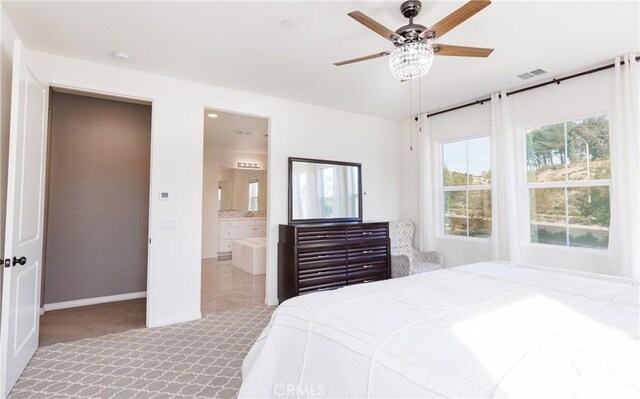 bedroom featuring light carpet, ensuite bath, and ceiling fan