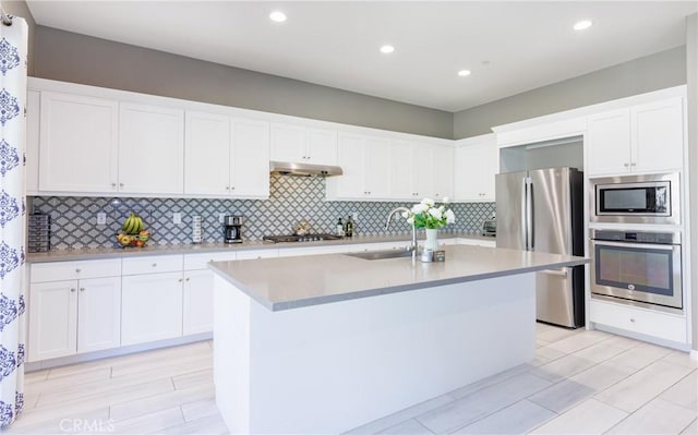 kitchen with white cabinetry, stainless steel appliances, a kitchen island with sink, and sink