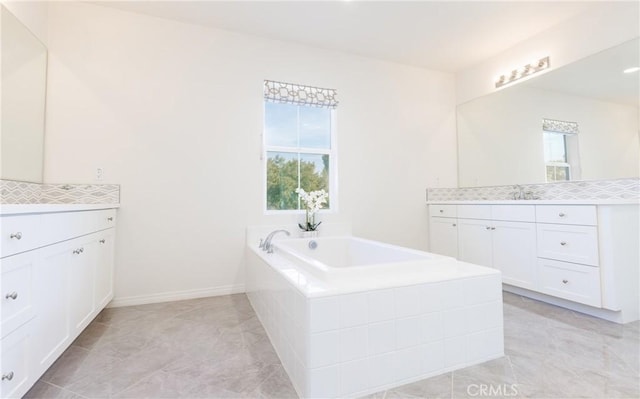 bathroom featuring vanity, tiled bath, and a wealth of natural light