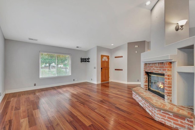 unfurnished living room featuring hardwood / wood-style flooring and a brick fireplace