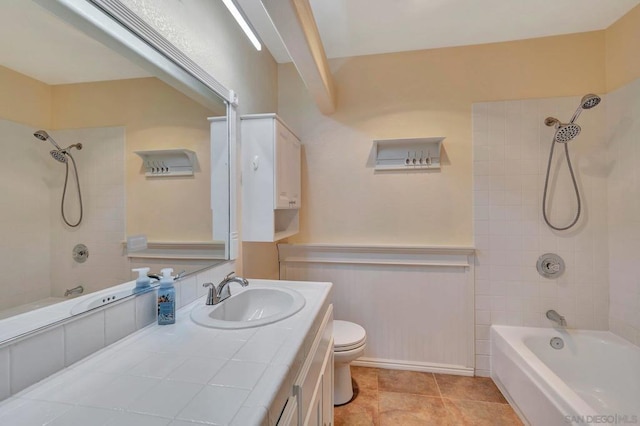 full bathroom with tile patterned flooring, tiled shower / bath, vanity, and toilet