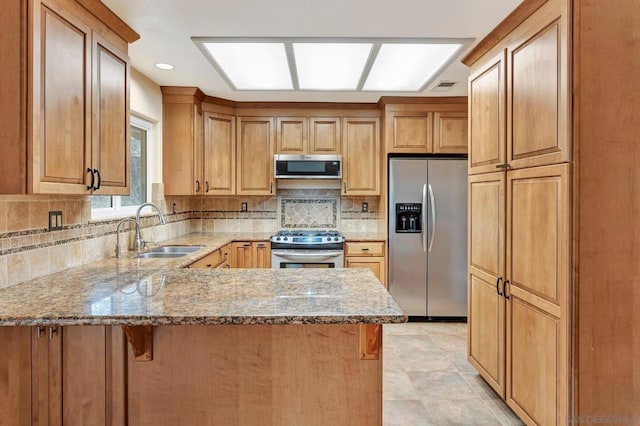 kitchen featuring sink, appliances with stainless steel finishes, kitchen peninsula, stone counters, and decorative backsplash