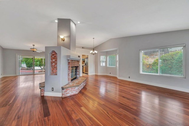 unfurnished living room with vaulted ceiling, a brick fireplace, and hardwood / wood-style floors