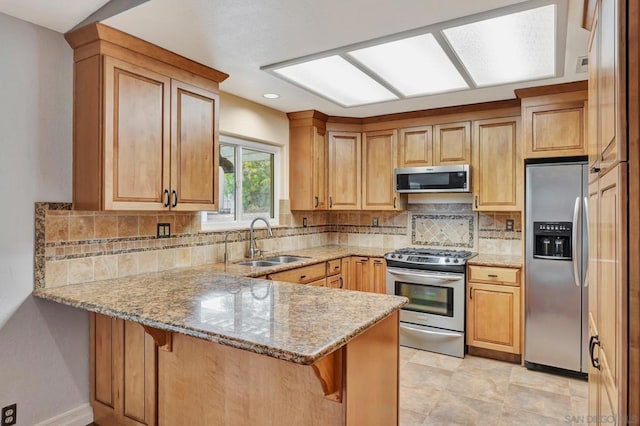 kitchen with light stone counters, stainless steel appliances, kitchen peninsula, and a breakfast bar