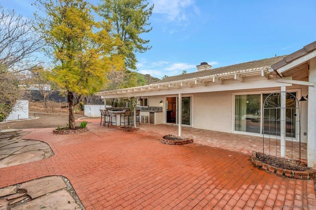 back of house with exterior kitchen, a patio, and a bar