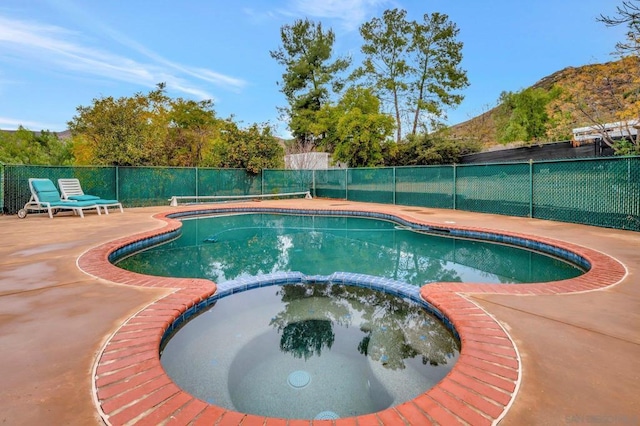 view of swimming pool featuring a mountain view, a patio area, and an in ground hot tub