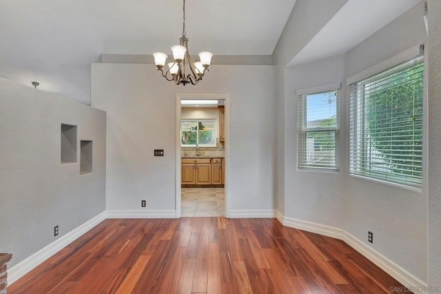 unfurnished dining area with vaulted ceiling, a chandelier, and dark hardwood / wood-style flooring