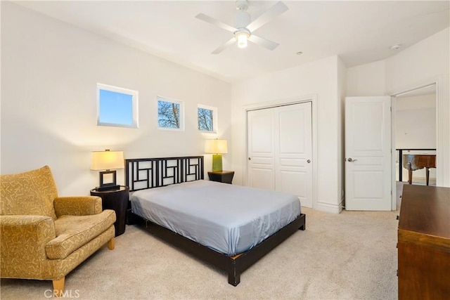 bedroom featuring light colored carpet, a closet, and ceiling fan