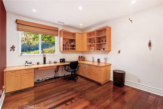 office with dark wood-type flooring and built in desk