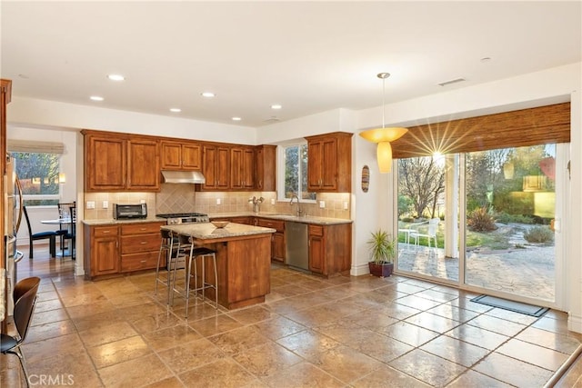 kitchen featuring pendant lighting, stainless steel appliances, a healthy amount of sunlight, and a kitchen island