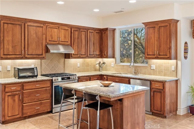 kitchen featuring a kitchen island, appliances with stainless steel finishes, a breakfast bar, sink, and light stone countertops