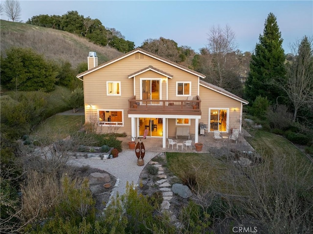 back of house featuring a wooden deck and a patio area