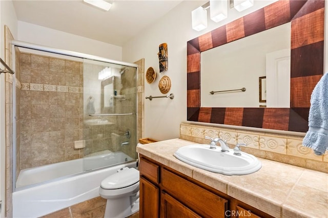 full bathroom featuring tile patterned floors, toilet, combined bath / shower with glass door, vanity, and decorative backsplash