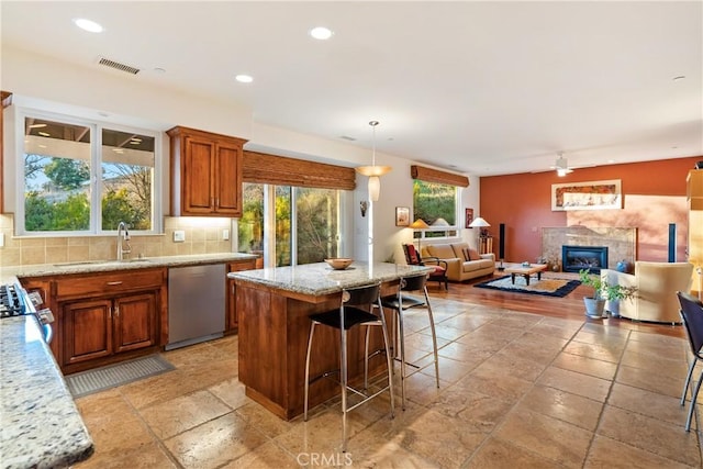 kitchen with pendant lighting, sink, stainless steel appliances, a center island, and tasteful backsplash