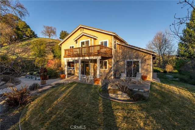 rear view of house with a deck, a patio area, and a lawn