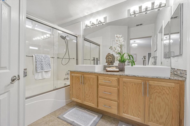 bathroom featuring enclosed tub / shower combo, vanity, tile patterned flooring, and backsplash