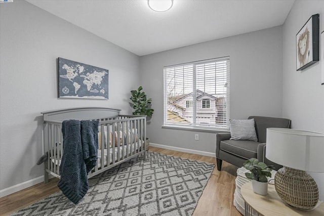 bedroom with hardwood / wood-style floors and a crib