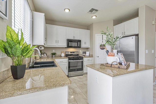 kitchen featuring white cabinetry, appliances with stainless steel finishes, sink, and light stone counters