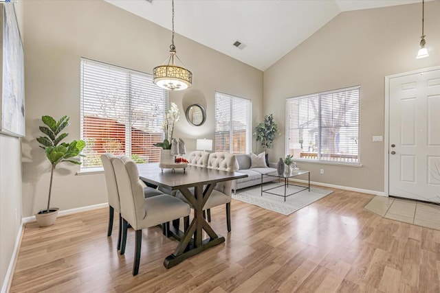 dining area featuring an inviting chandelier, high vaulted ceiling, and light hardwood / wood-style floors