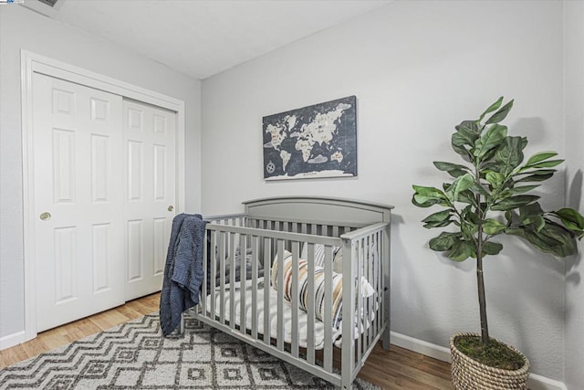 bedroom with a crib, hardwood / wood-style flooring, and a closet