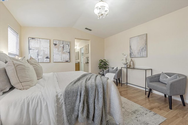 bedroom with a notable chandelier, vaulted ceiling, and light wood-type flooring