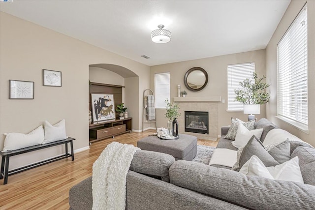 living room featuring a tiled fireplace and light hardwood / wood-style floors