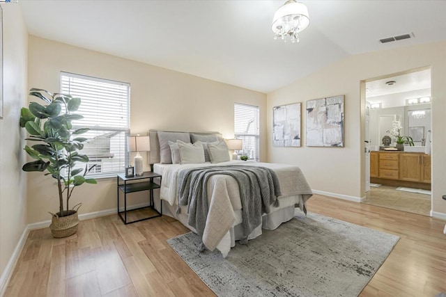 bedroom featuring multiple windows, ensuite bathroom, lofted ceiling, and light wood-type flooring