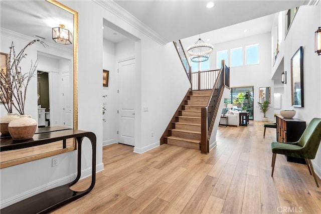 entrance foyer with crown molding, a notable chandelier, and light wood-type flooring