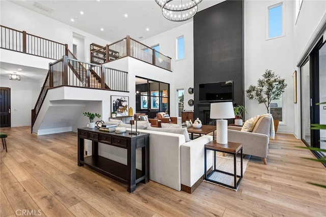 living room featuring an inviting chandelier, a towering ceiling, and light hardwood / wood-style floors