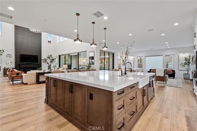 kitchen featuring pendant lighting, sink, light hardwood / wood-style flooring, and a large island with sink