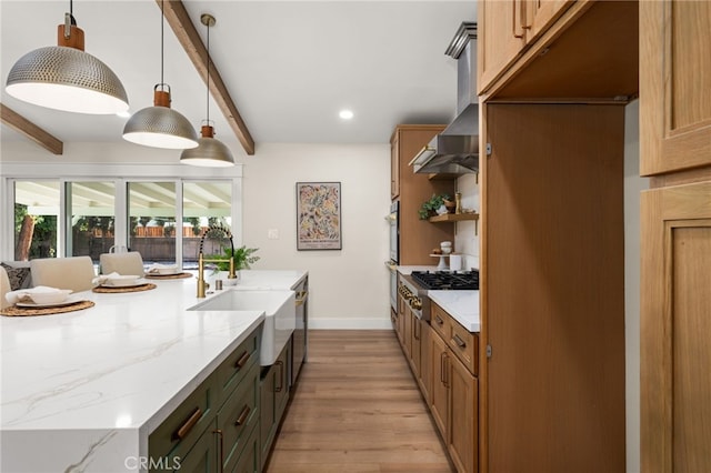 kitchen featuring decorative light fixtures, beamed ceiling, stainless steel gas stovetop, sink, and light stone countertops