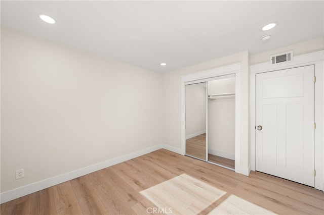 unfurnished bedroom with a closet and light wood-type flooring