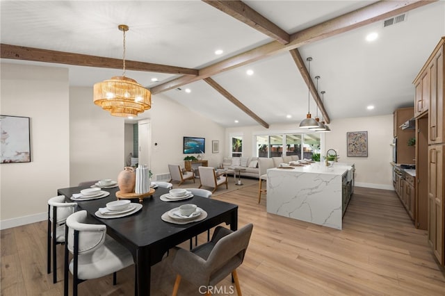 dining space featuring sink, lofted ceiling with beams, and light hardwood / wood-style flooring