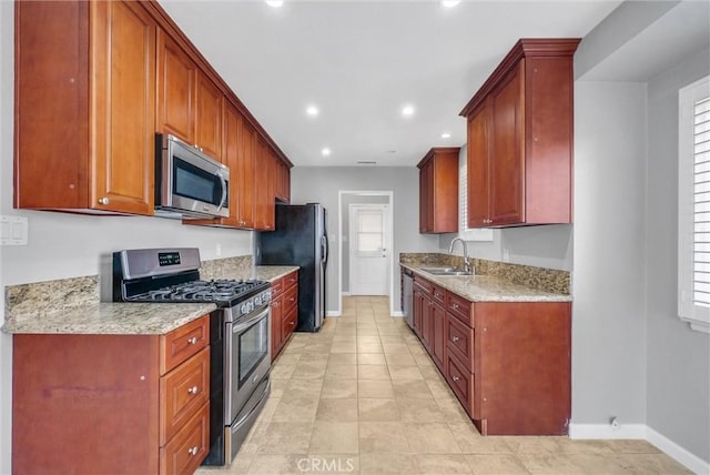 kitchen featuring recessed lighting, stainless steel appliances, a sink, baseboards, and light stone countertops