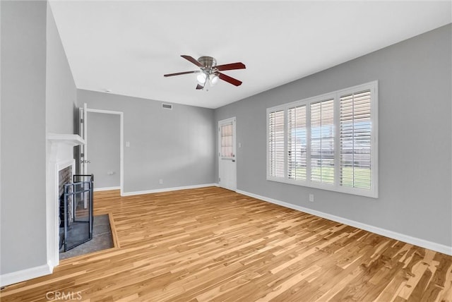 unfurnished living room with a fireplace with flush hearth, visible vents, a ceiling fan, baseboards, and light wood-type flooring