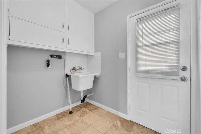 clothes washing area with hookup for a washing machine, cabinet space, plenty of natural light, and baseboards