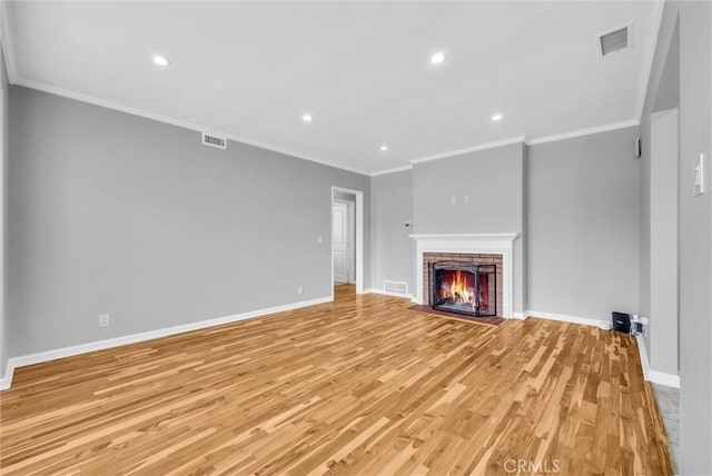 unfurnished living room with light wood-style flooring, a brick fireplace, visible vents, and baseboards