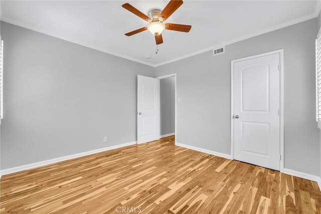 unfurnished bedroom featuring baseboards, crown molding, visible vents, and light wood finished floors