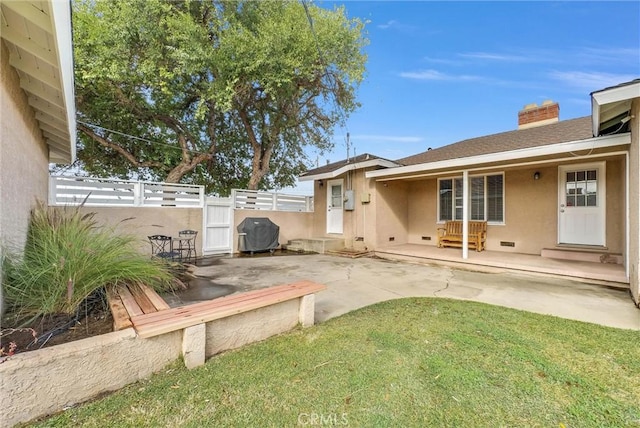 exterior space with fence, a yard, stucco siding, a chimney, and a patio area