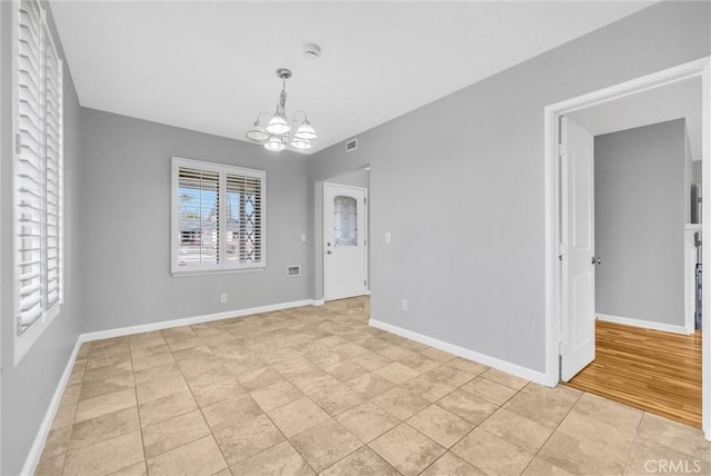 tiled spare room with an inviting chandelier